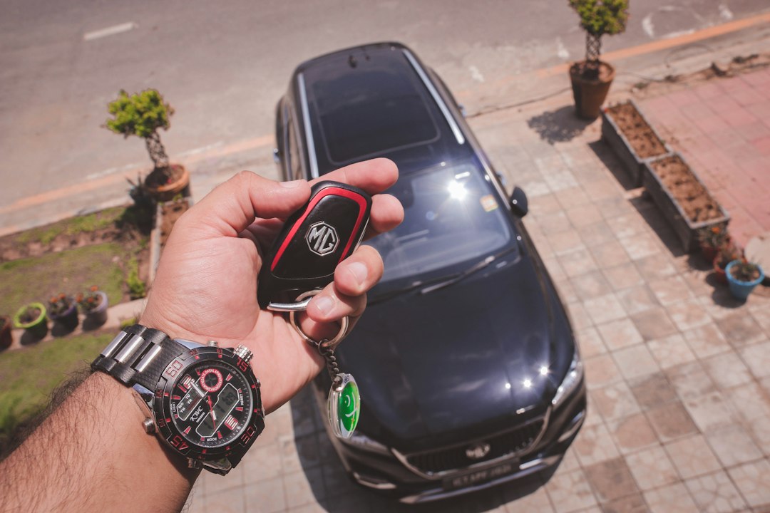 Mão segurando a chave de um carro estacionado
